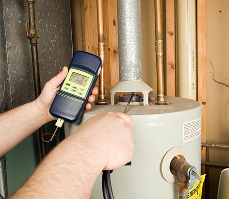 Technician holding a monitoring device next to a water heater