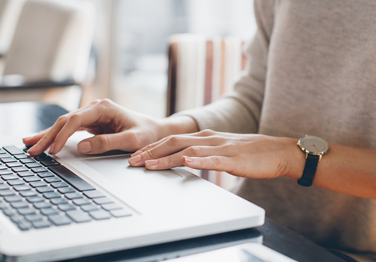Close up of woman’s hands typing on a laptop computer
