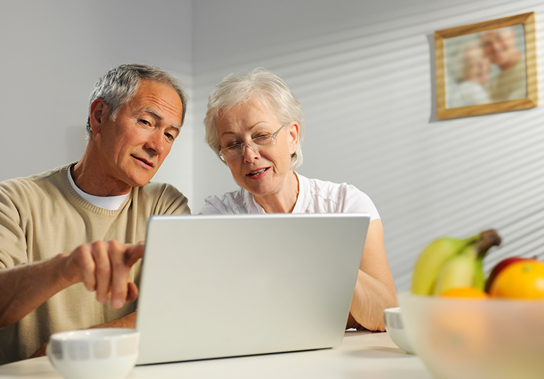 Retired couple viewing online account information on a laptop