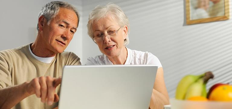 Retired couple viewing online account information on a laptop