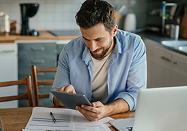 Man sitting at a table looking at a tablet