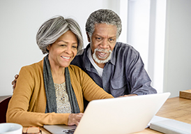 Older couple sitting and looking at a laptop