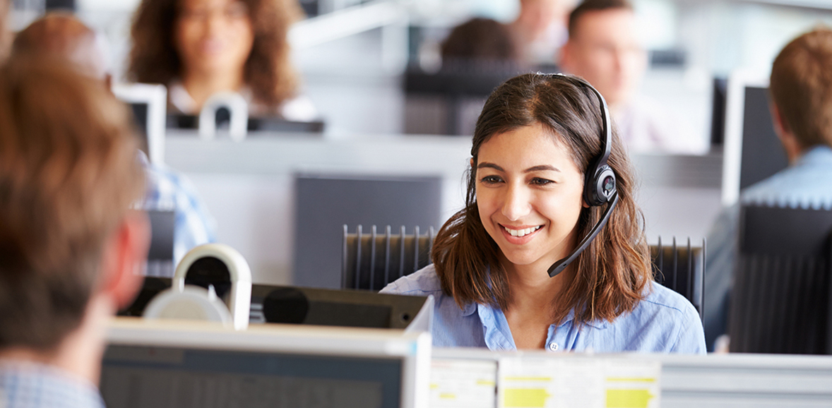 Smiling woman sitting in a call center, wearing a headset
