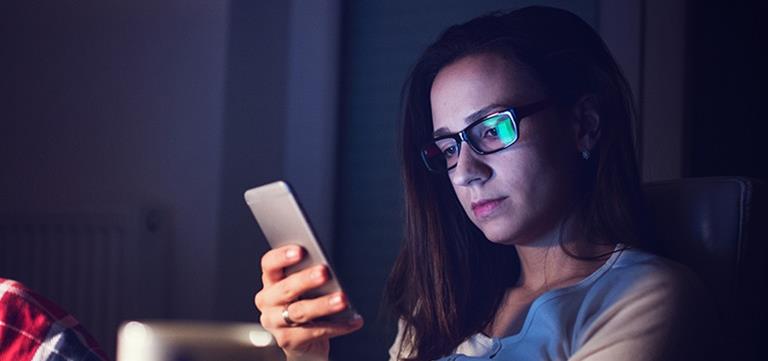 Woman sitting in dark room looking at smart phone
