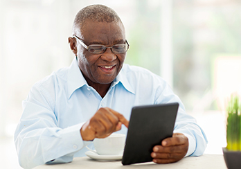  A man sitting at a table using a tablet device