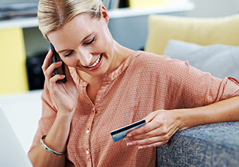  A woman talking on the phone and holding and looking at a credit card