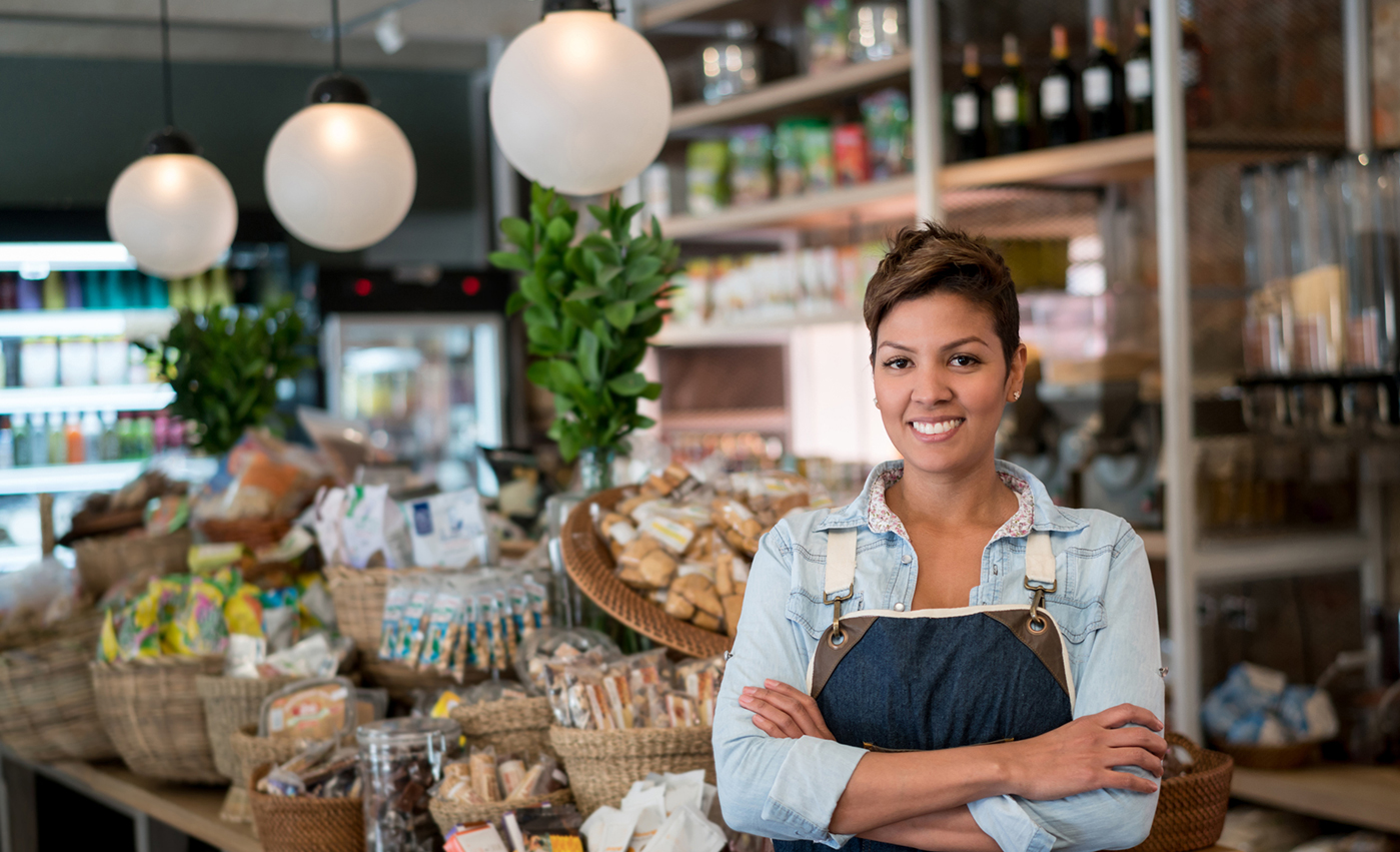 Woman wearing an apron standing in front of food display