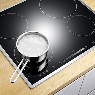 A black ceramic cook top with a pan on one of the burner