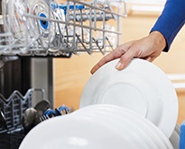 A person putting a plate into a dishwasher