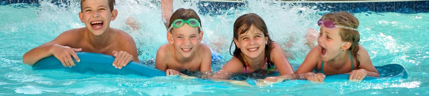 Two kids smiling while playing in a swimming pool