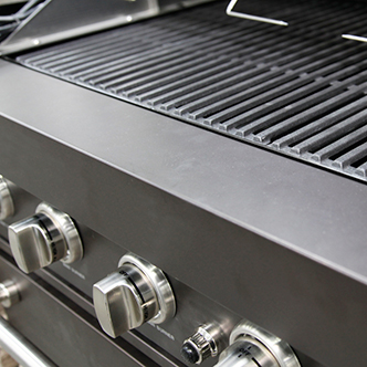 A closeup of the grates and dial on a gas grill