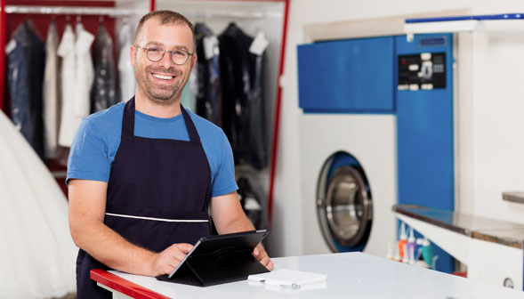 Male small business laundromat owner using tablet